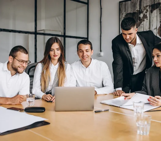 Team of colleagues smiling at a laptop around a meeting table