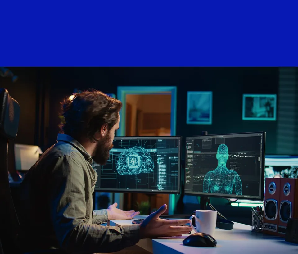 A developer at a desk with two monitors showing AI brain and body scans